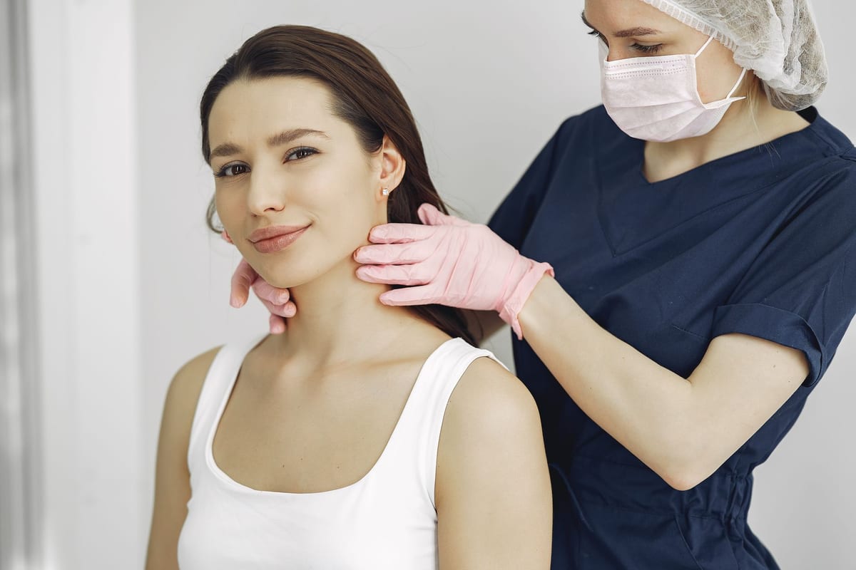A clinician in gloves examining a patient's neck